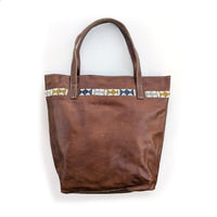 Leather tote bag with metallic geometric beaded design along the top.