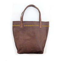 Brown leather tote bag with gold beaded circles along the top.