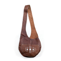 Brown leather sling bag with white beaded geometric details on white background.
