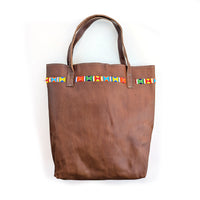 Leather tote bag with colorful geometric beaded design along the top.