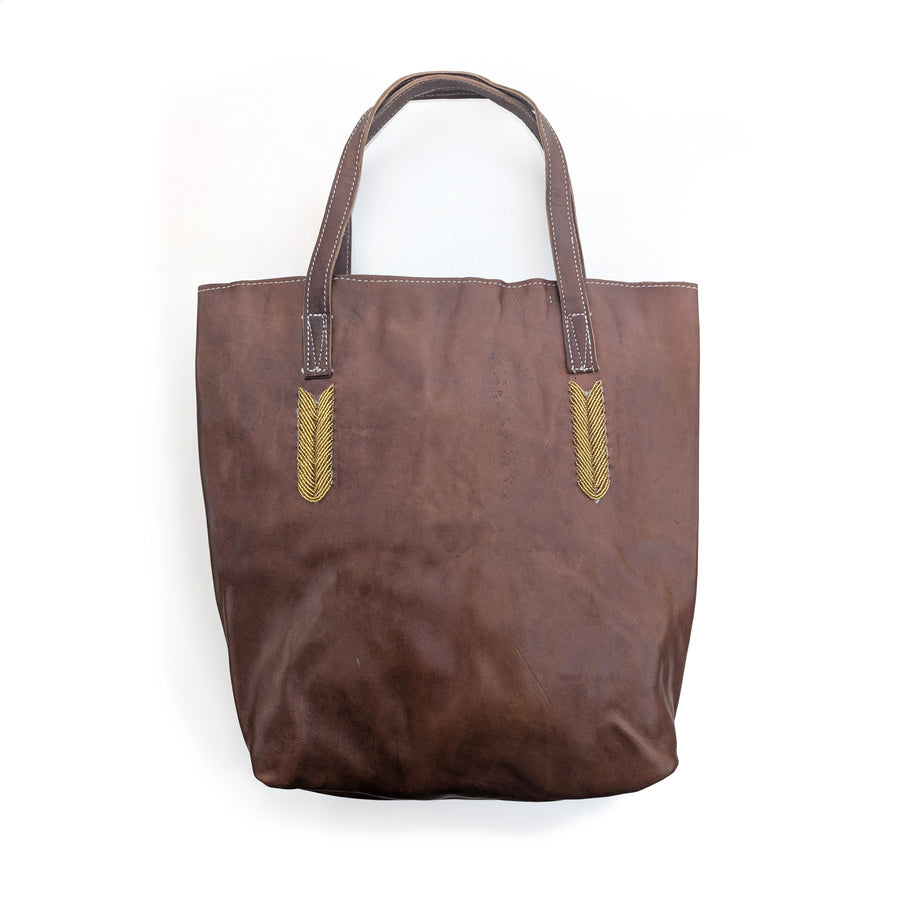 Brown tote bag with gold beaded accents on a white background