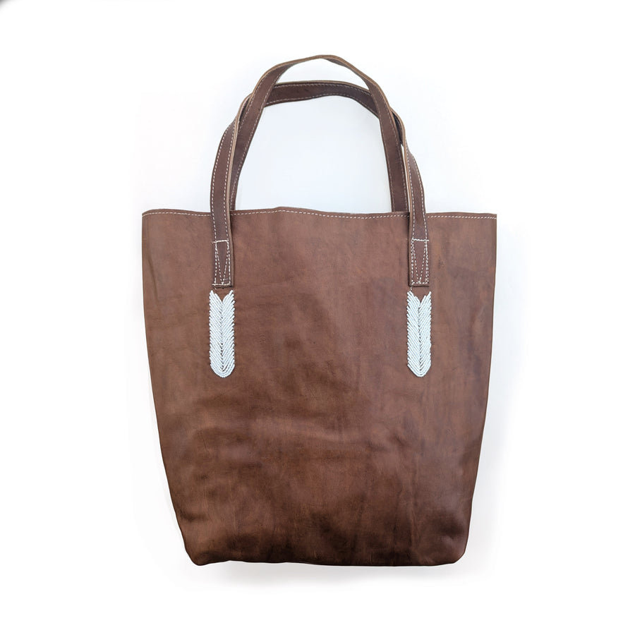 Brown tote bag with white beaded accents on a white background