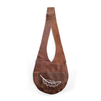 Brown leather sling bag with white beaded fern design on white background.