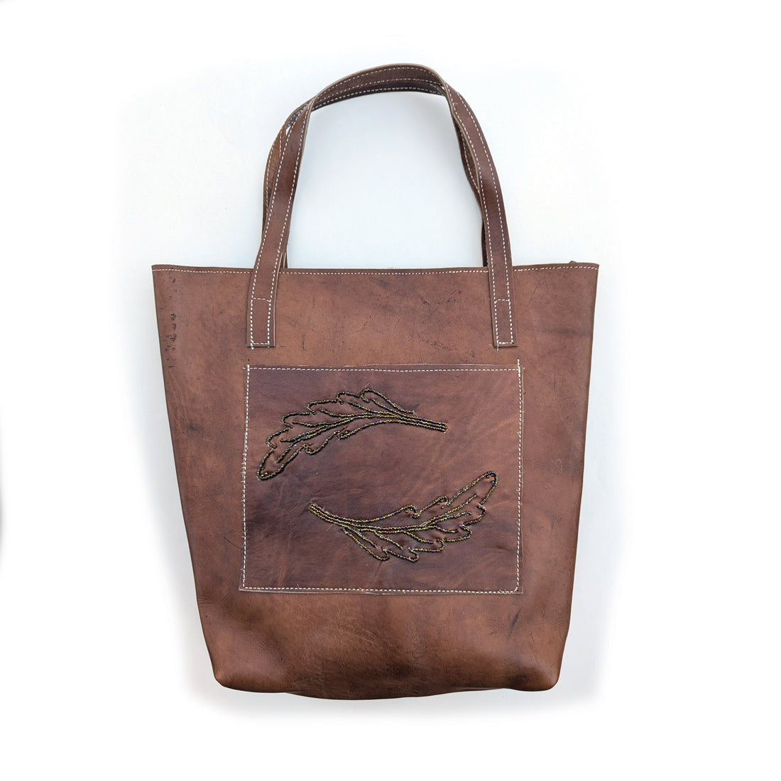 Leather tote bag with front pocket and brown rainbow beaded fern leaf design.