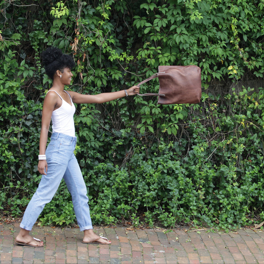 Woman holding a brown bag against a green leafy background