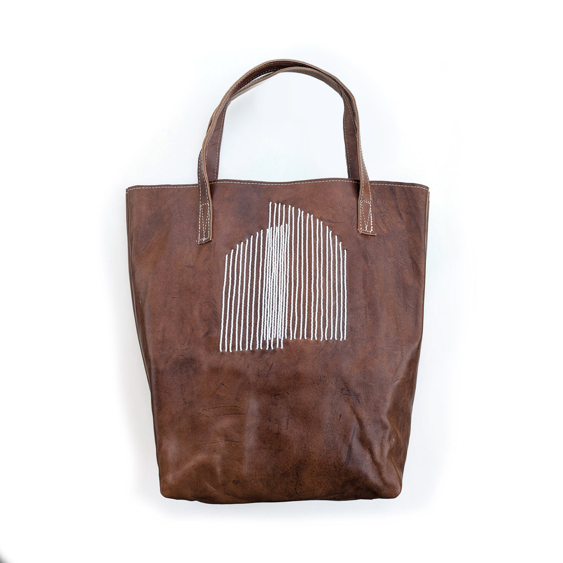 Brown leather tote bag with white arc beading.