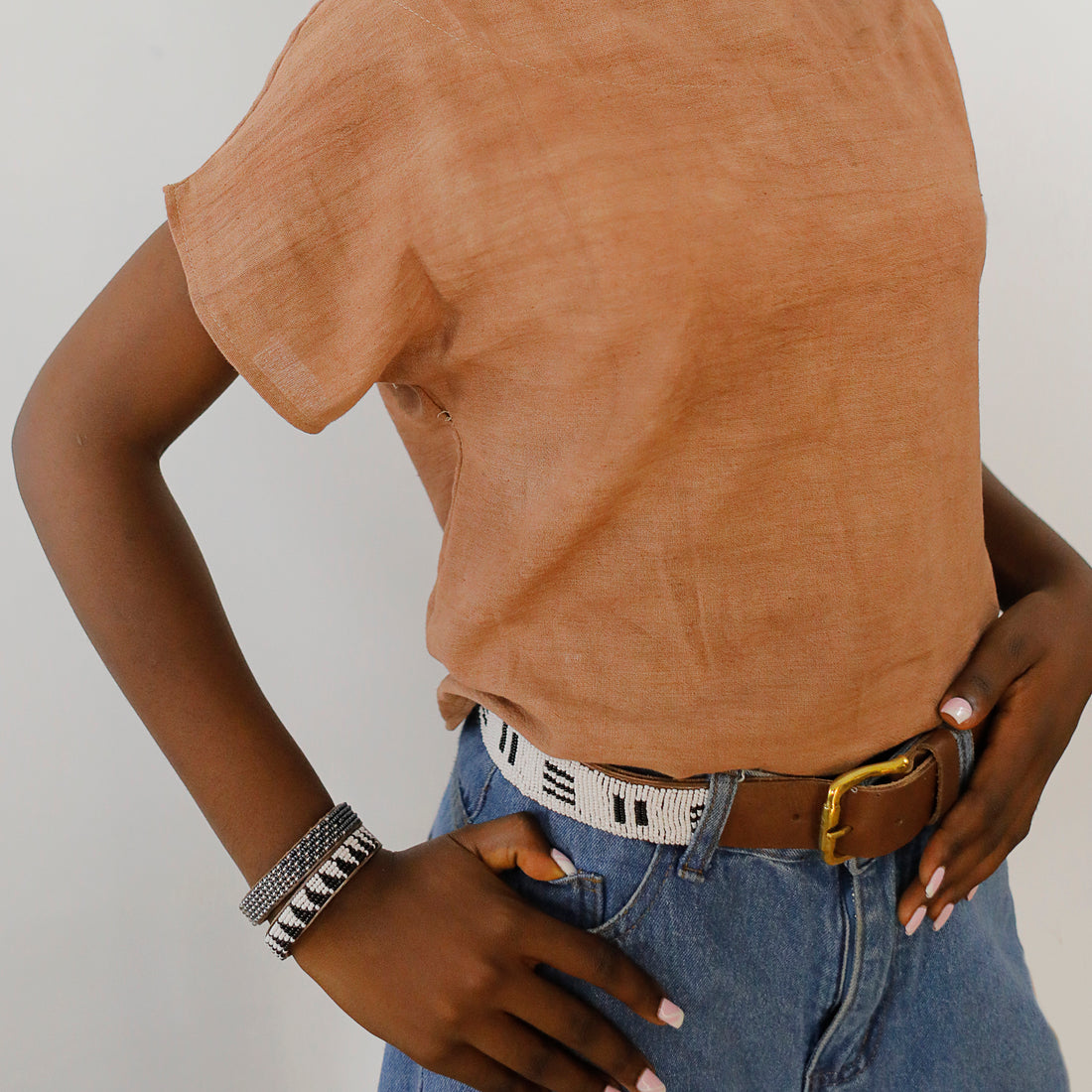 Front of black and white stitches belt and buckle on model.
