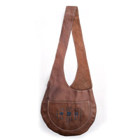 Brown leather sling bag with slate beaded geometric details on white background.