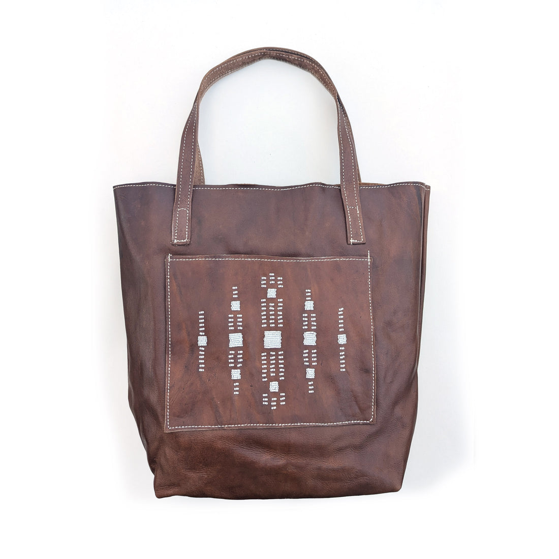 Leather tote bag with square front pocket and white geometric beaded design.