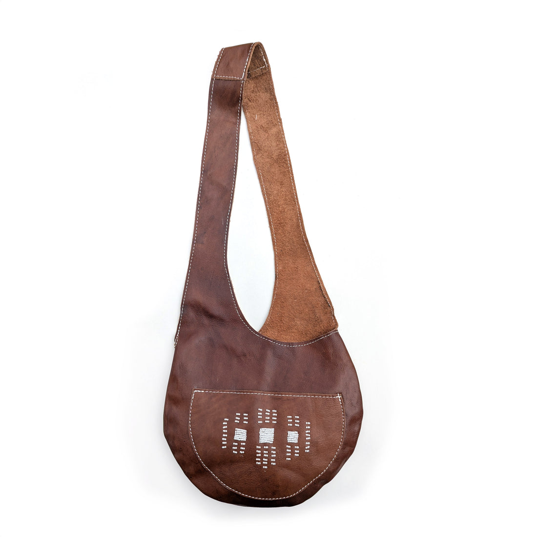 Brown leather sling bag with white beaded geometric details on white background.